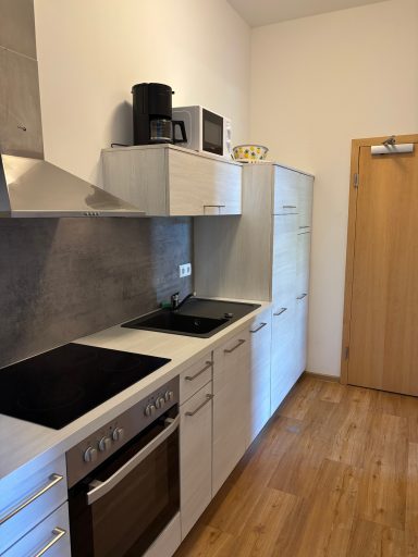 Moderne Küche mit Herd, Mikrowelle, Schränken und Holzfußboden.