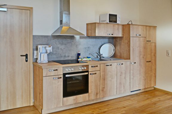 Moderne Küche mit Holzschränken, Herd, Kühlschrank und Mikrowelle.