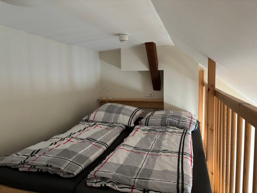 Gemütliches Schlafzimmer mit einem Doppelbett und Gitterwand in einem Dachgeschoss.