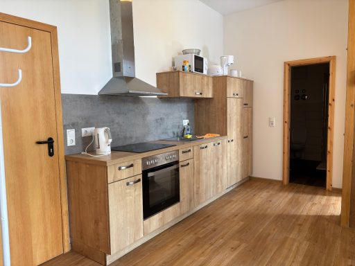 Moderne Küche mit Holzschränken, Herd, Spüle und offenen Regalen. Raumhelligkeit.